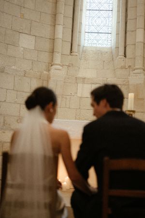A bride and groom hold hands at the altar of a stone church during their wedding ceremony.
