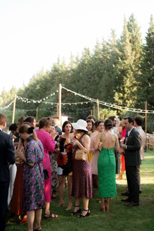 Wedding guests dance under string lights at an outdoor evening reception.