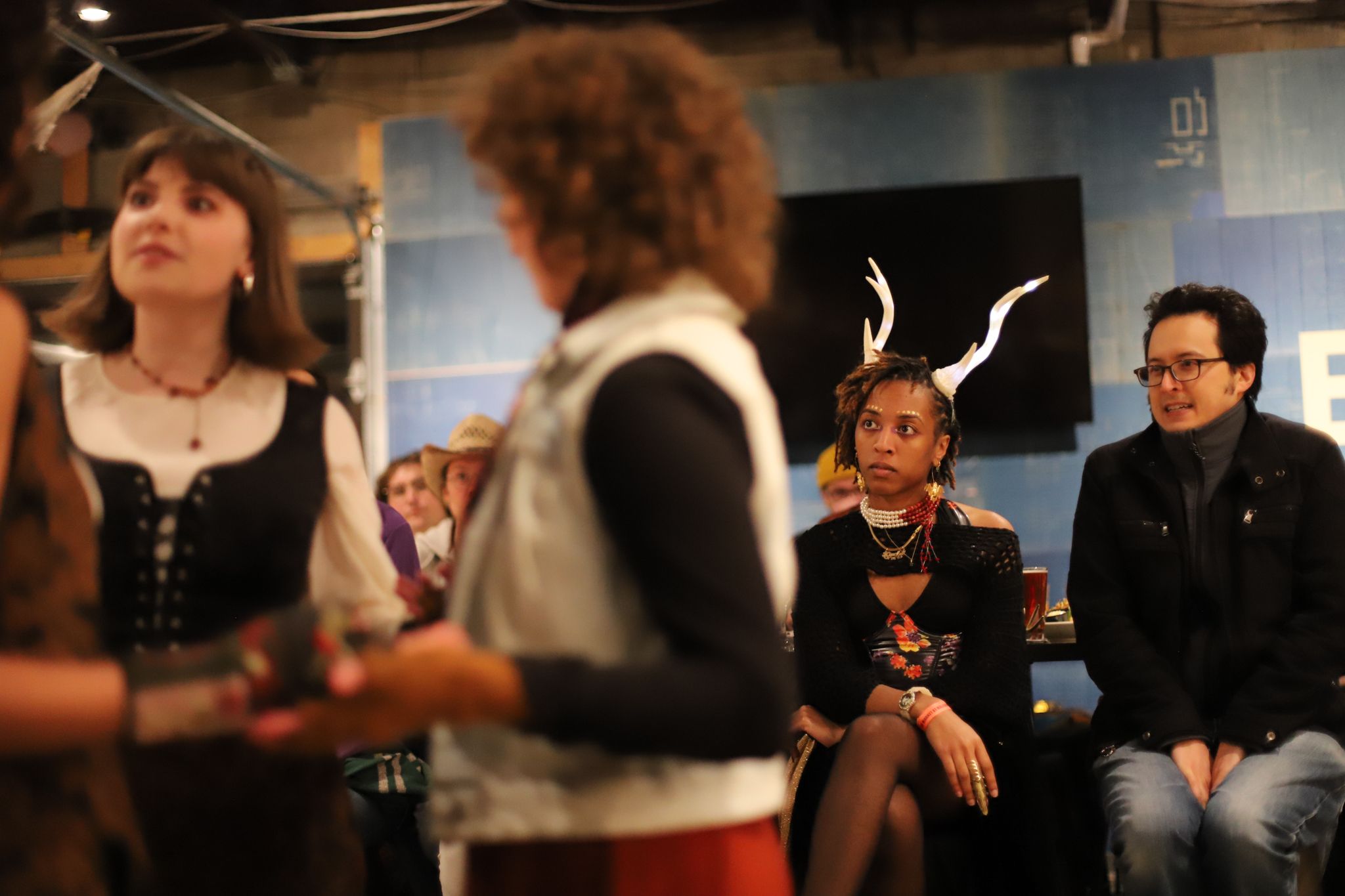 A group of people gather in what appears to be a backstage or studio setting with dim lighting.