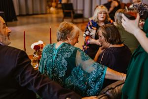 Wedding guests in formal attire gathered at reception tables decorated in teal and dark colors.