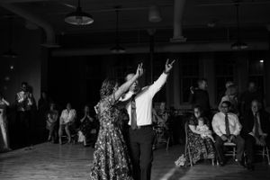 A black and white photo of dancers twirling energetically on a dance floor while others watch from the sidelines.