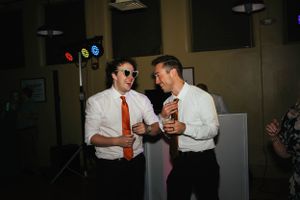 Two guests in formal attire sharing drinks and laughs at an evening celebration.