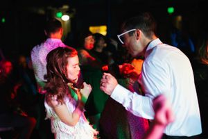 Couple dancing together under colorful party lights at an evening celebration.
