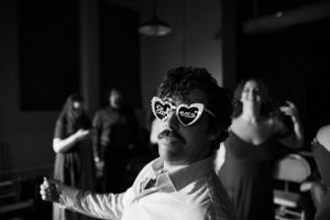Person wearing heart-shaped novelty glasses dancing at a dark party venue.