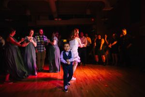 Dancers move across a wooden dance floor under dramatic red and blue lighting at a social dance event.