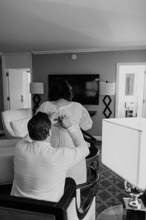 A couple seated in a hotel room sharing an intimate moment in black and white.