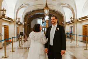 A couple share an intimate moment in an elegant hallway with arched ceilings and hanging lanterns.