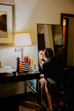 A lamp illuminates a makeup vanity setup with assorted beauty products in a dimly lit room.
