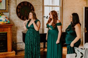 Wedding party members in emerald green dresses performing in front of a vintage clock.