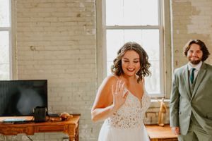 Joyful wedding scene in a bright loft space with white brick walls and rustic decor.