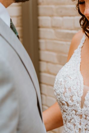 Close up detail of wedding attire showing gray suit and white lace dress.