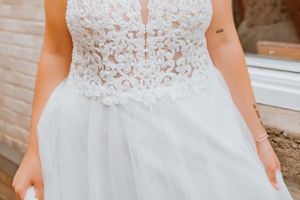 Detailed view of white lace wedding dress bodice with delicate pattern and plunging neckline.