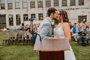 A tender moment shared during an outdoor wedding ceremony with guests seated on the lawn.
