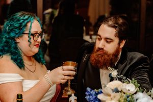 A couple shares a toast at their wedding reception with blue floral centerpieces on the table.
