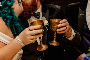 Wedding couple toasting with golden chalices during celebration.