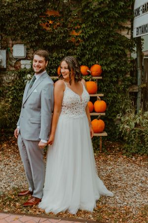 Fall wedding portrait with decorative pumpkins and ivy backdrop.