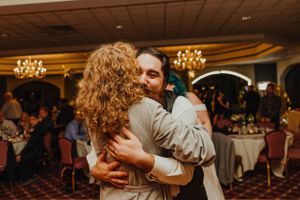Couple sharing an intimate embrace during their wedding reception in an elegantly lit ballroom.