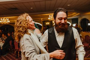 A couple shares a joyful moment while dancing together at an elegant reception venue with warm lighting.