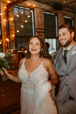 A couple shares a joyful moment during their wedding celebration in an industrial rustic venue.
