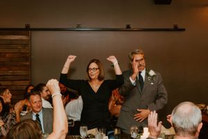 Wedding guests and party members celebrate enthusiastically during a reception dinner.