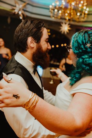 A couple dancing together at an event with twinkling lights and stars hanging from the ceiling.