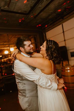 Newlyweds sharing an intimate dance moment under red mood lighting at their wedding reception.