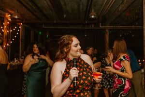 Partygoers dance and socialize at a dimly lit indoor venue decorated with string lights.