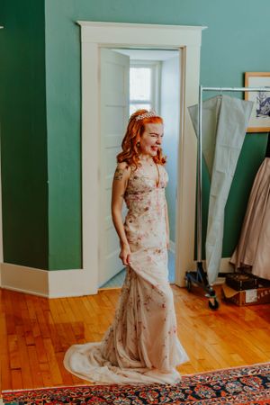 A stunning floral embellished wedding gown with a fitted silhouette photographed in a room with green walls.