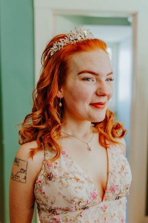 Elegant bridal portrait with vintage-inspired floral dress and crystal crown against mint green walls.