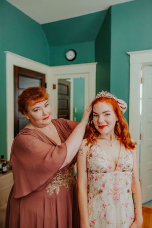 Two people in a mint green room during what appears to be a formal preparation.