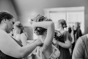 Black and white photo showing preparation before a formal event with helpers styling hair.