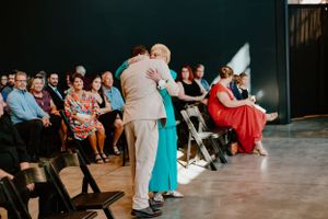 Wedding guests dancing enthusiastically at a reception in a dimly lit venue.