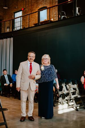 A formal event in an industrial venue with brick walls and folding chairs set up for guests.