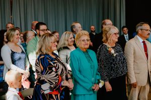 People gathered at a formal event, with someone wearing a striking turquoise blazer standing in the center of the group.