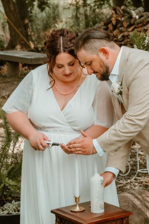 A couple shares an intimate moment while reading something together at their outdoor wedding ceremony.