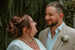 A loving couple exchanges glances during their wedding day celebration against a backdrop of weeping willow trees.