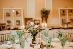 Wedding reception table decorated with rustic centerpieces featuring baby's breath flowers and mint green napkins.