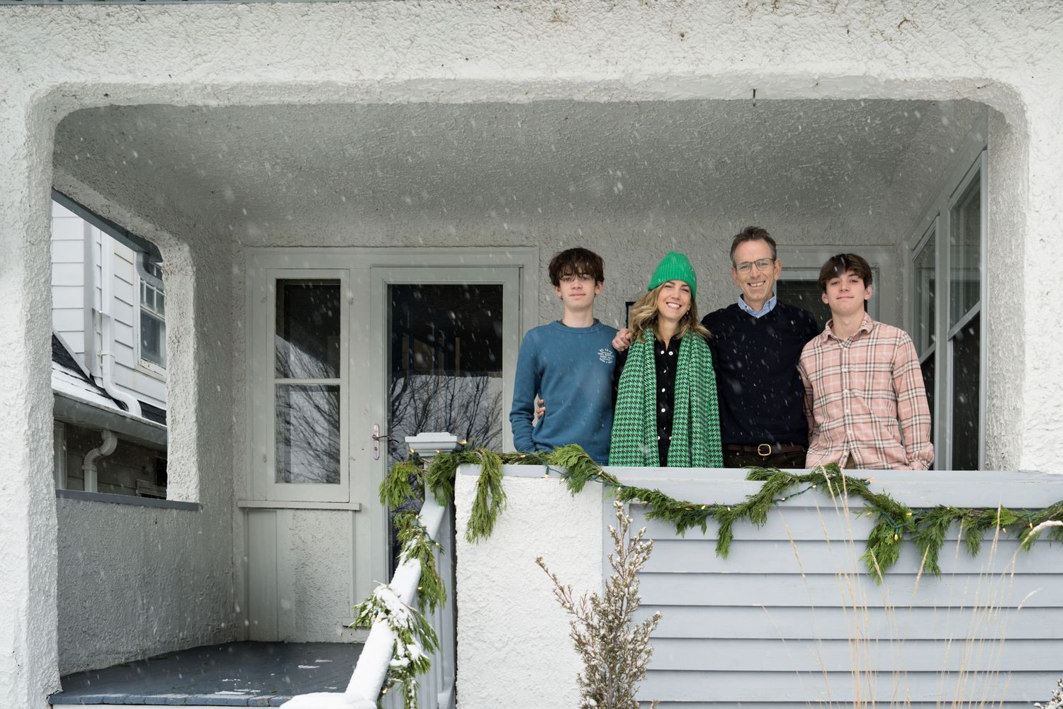 Family photo by Milwaukee family photographer Rachel Dickman of a family on their front porch during a snowstorm.