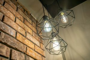 Geometric pendant lights with exposed bulbs hanging against exposed brick wall creating industrial ambiance. Cadillac Hotel Boutique.
