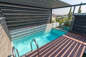 Rooftop infinity pool with cascading water feature and modern architectural elements. Cadillac Hotel Boutique.