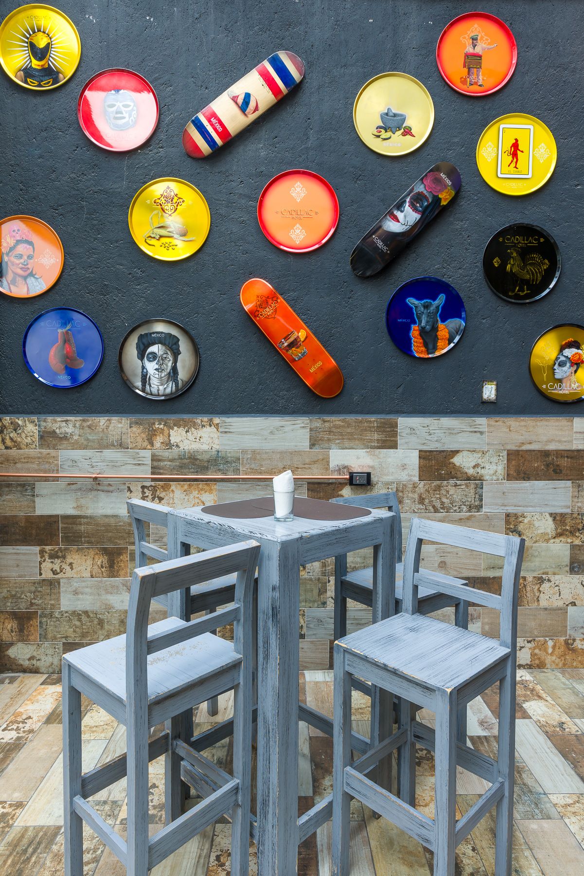 Bar seating area with decorative vintage pins and skateboard elements mounted on dark wall. Cadillac Hotel Boutique.