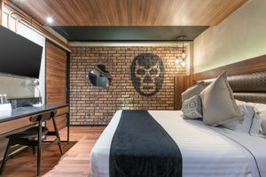 Stylish hotel room with exposed brick wall, mounted TV, and black and white bedding. Cadillac Hotel Boutique CDMX.