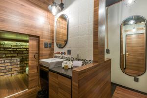 Modern bathroom interior with wooden walls, oval mirrors, and concrete sink features industrial-chic design elements.