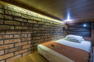 A cozy bedroom with exposed brick walls and ambient lighting features a comfortable bed with brown accents.