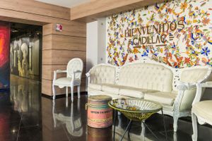 Elegant lounge area with white vintage furniture and colorful 'Bienvenidos' wall mural in Latin American style decor.