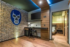 Contemporary hotel room workspace with lucha libre mask decor and wood paneled walls. Cadillac Hotel Boutique CDMX.