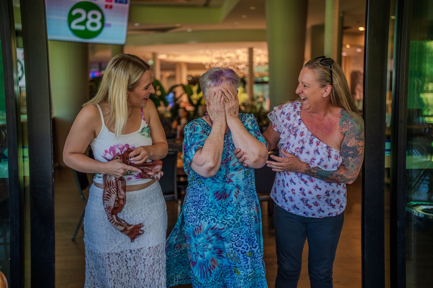 Three people sharing an emotional moment and laughter together indoors.