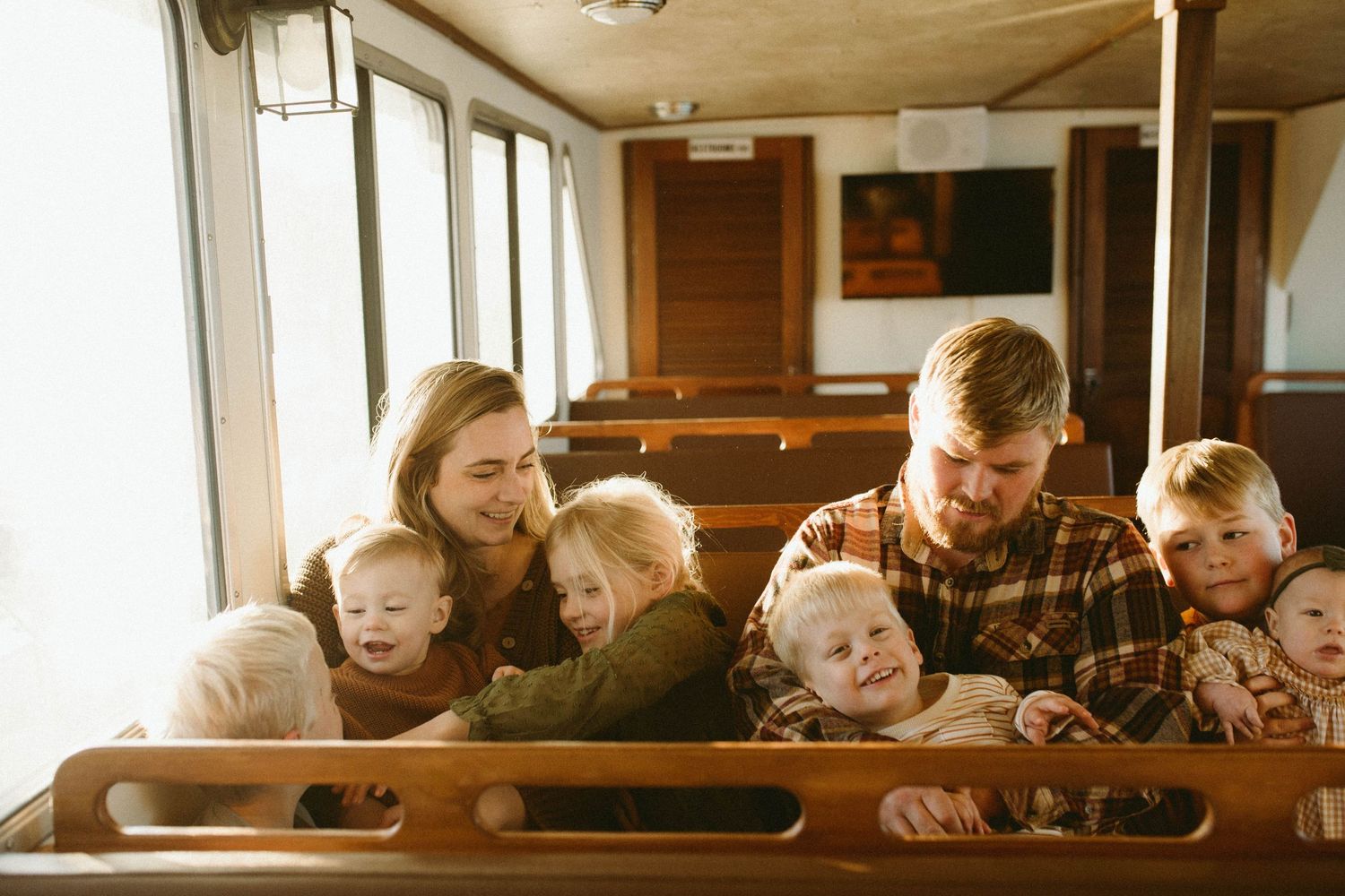 Photo by B.Logsdon of a family siting together in a sunlit boat, on the May River laughing and enjoying each other.