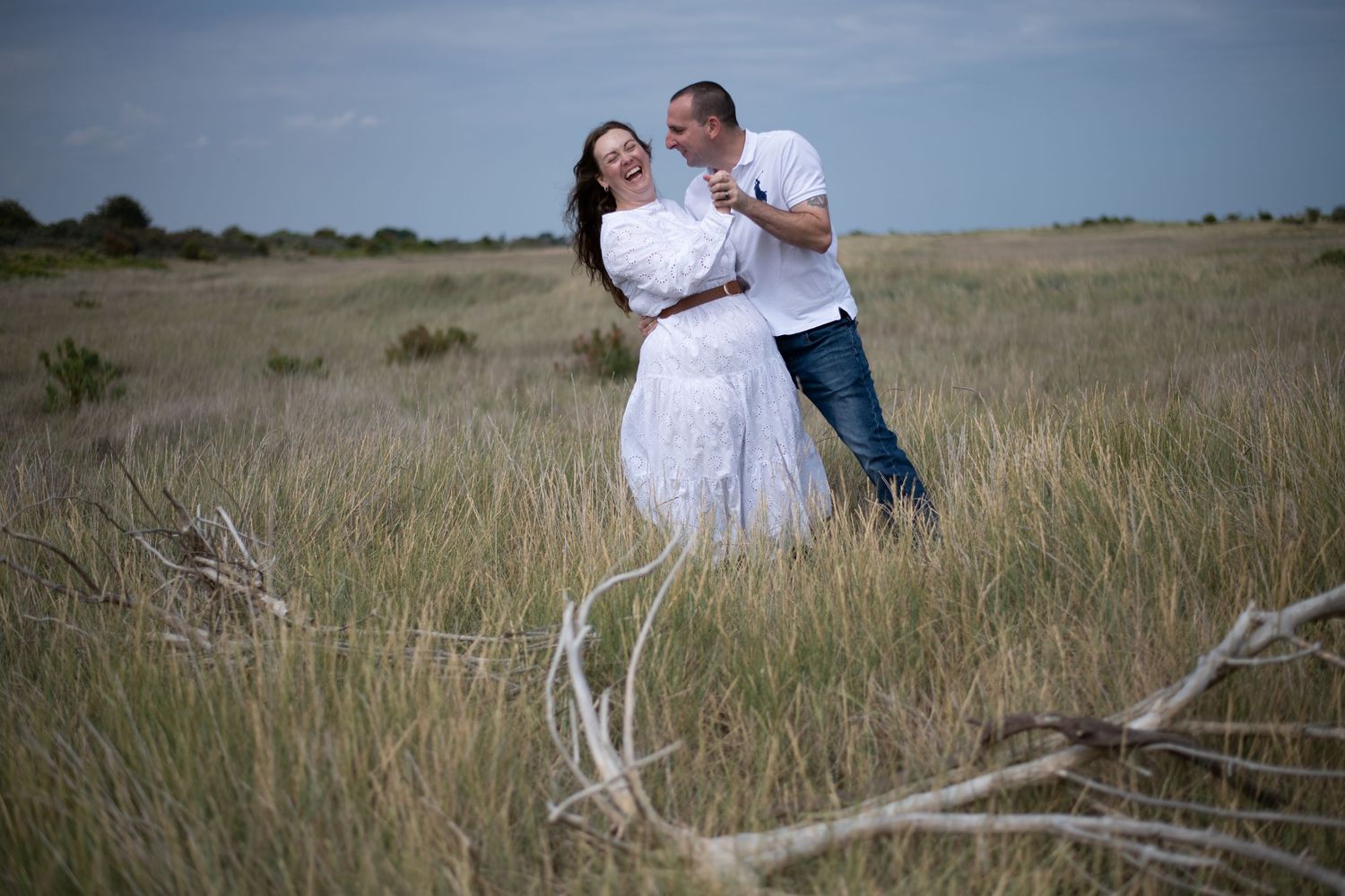 Happy couple dancing and laughing together in golden grass prairie field.