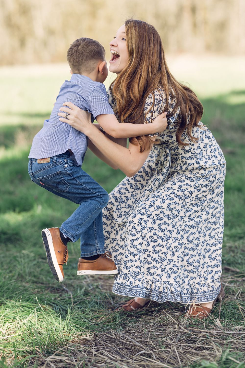 A mother laughs with delight as her young son jumps into her arms outdoors.